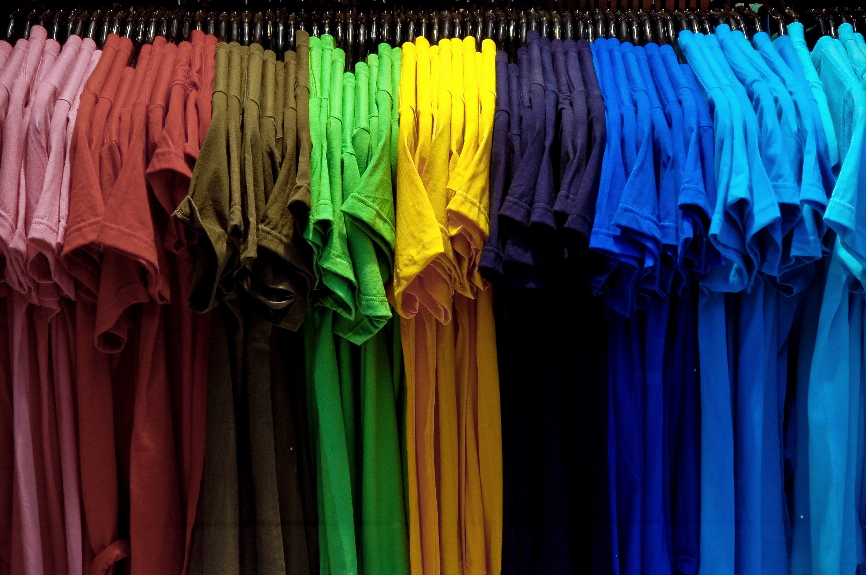 Футболки в гардеробе. Футболка на вешалке. Много футболок на вешалке. Одежда разного цвета. Цветные футболки на плечиках.